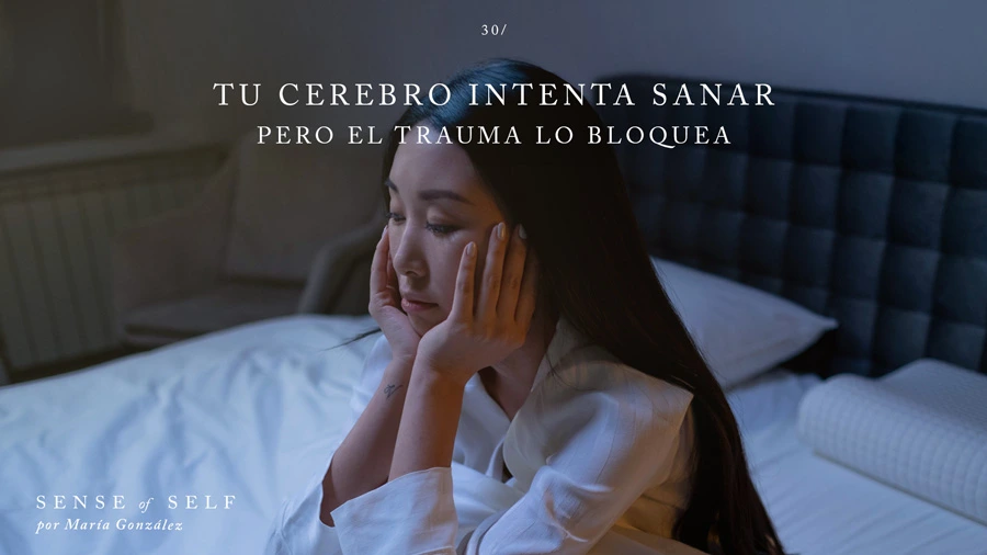 Una mujer sentada en la cama en mitad de la noche con cara abatida tras despertarse en alerta por una pesadilla.